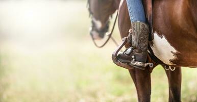 detalle de un adornado vaquero botas en un estribo mientras sentado en un caballo foto