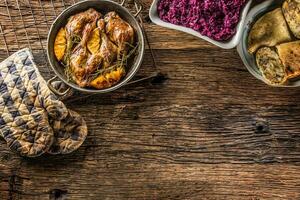 Roasted duck legs in pan with oranges herbs red cabbage and pota photo