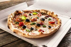 Pizza in a cardboard box on table ready to customer. photo