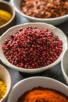 Pink peppercorn and variety spices and herbs in bowls photo