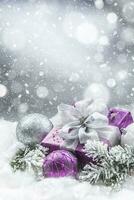 Purple christmas gift and balls on snow with fir branches. Merry Xmas concept photo