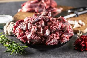 Fresh beef shank cuts piled in a bowl on a dark surface with herbs and spices around photo