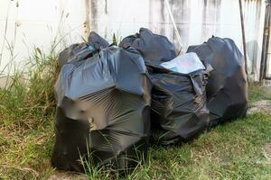 Black plastic garbage bags on the grass in the yard of the house photo