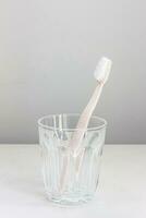 Pink toothbrush in a glass placed on a white background photo