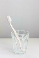 Pink toothbrush in a glass placed on a white background photo