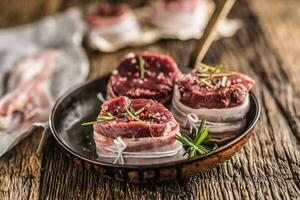 Beef tenderloin steak wrapped in bacon stored into the pan photo