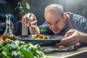 A professional chef decorates a meal just before serving it to a customer in a restaurant pub or hotel photo