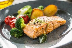 Roasted salmon fillet broccoli tomatoes and fried potatoes with dill cream sauce photo