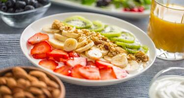 Healthy breakfast served with plate of yogurt muesli kiwi strawberries and banana photo
