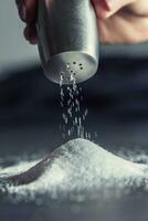 Female hand pouring salt from staniless salt shaker photo