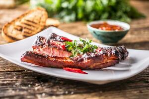 Tasty barbecue grilled pork ribs with chili pepers and parsley herbs. photo