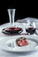 Beef tenderloin steak on white plate and red wine in pub or restaurant photo