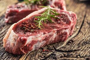 Beef Rib Eye steak with salt pepper and rosemary on wooden table photo