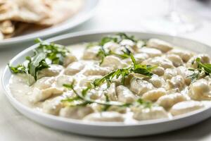 Gnocchi ai quattro formaggi, Italian dough pasta with four types of cheese and ruccola on top photo