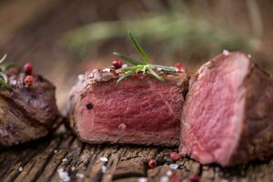 Grilled beef steak with rosemary, salt and pepper on old cutting board. Beef tenderloin steak. photo