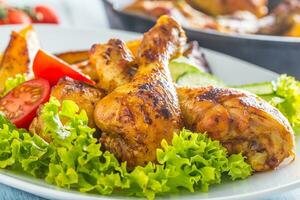 Roasted chicken legs with lettuce salad and tomatoes photo