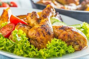 asado pollo piernas con lechuga ensalada y Tomates foto