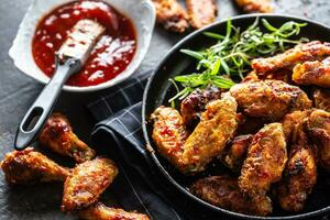 Chicken wings barbeque in a cast iron baking dish with BBQ sauce and rosemary photo