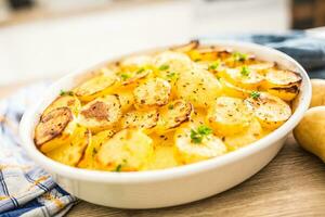 Roasted potatoes with spices and herbs on kitchen table photo