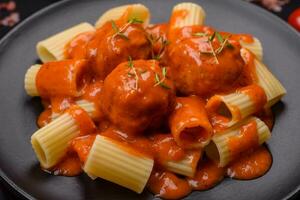 Delicious fresh meatballs and pasta in tomato sauce with salt, spices and herbs photo