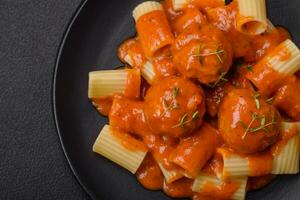 Delicious fresh meatballs and pasta in tomato sauce with salt, spices and herbs photo