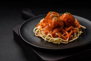 Delicious fresh meatballs and pasta in tomato sauce with salt, spices and herbs photo