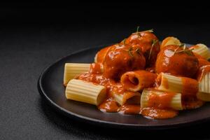 Delicious fresh meatballs and pasta in tomato sauce with salt, spices and herbs photo