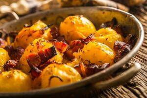 papas. asado patatas con tocino cebolla y salchichas en antiguo roble mesa foto