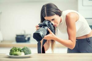 mujer profesional fotografiando plato con brócoli. comida fotógrafo trabajando en cocina estudio foto