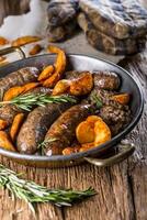 Sausages.Roasted pork sausage in a pan with potatoes and rosemary. photo