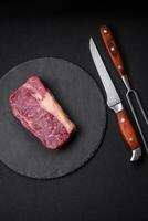 Fresh raw beef striploin steak with salt, spices and herbs photo