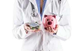 Doctor woman hands holding pills and piggy bank photo