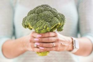 The hands of a young woman hold a fresh broccoli photo