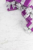 Navidad púrpura regalos con plata cinta en mármol mesa foto