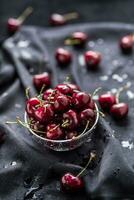 Sweet ripe cherries on dark tablecloth with water drops photo