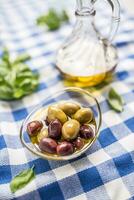 Green and red olives in bowl with olive oil and carafe in the background photo