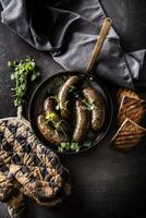 Roasted sausages in pan with bread and herbs. photo