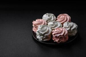 Delicious sweet multi-colored marshmallow on a dark concrete background photo