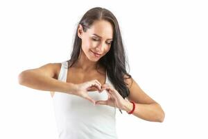 Beautiful brunette in a white shirt doing a heart sign in front of her chest pretending love and peace to the world. Isolated background photo