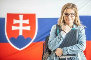 Beautiful student holds studying material with Slovak flag in the back photo