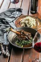 Roasted or confit Lamb Leg in pan with spinach and red wine photo