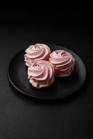 Delicious sweet colored marshmallow on a dark concrete background photo