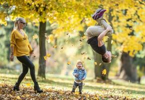 papá haciendo voltereta hacia atrás hace su hijo y esposa risa durante un divertido otoño día en teh naturaleza foto