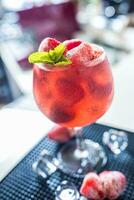 Strawberry lemonade or alcoholic cocktail with ice syrup soda and mint leaves on bar table photo