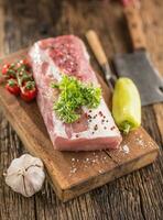 Pork loin fillet parsley herb tomatoes pepper garlic salt and spices on wooden kitchen board. photo