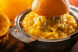 Freshly squeezed orange in a manual juicer with pulp photo