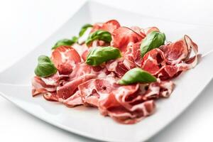 Prosciutto. Curled slices of delicious Italian Prosciutto with basil photo