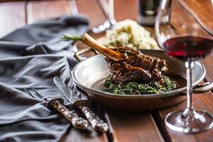 Roasted or confit Lamb Leg in pan with spinach and red wine photo