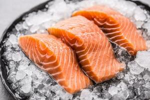 Portioned raw salmon fillets in ice on plate - Close-up. photo