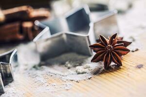 Star anise cookie cutter cinnamon and flour on baking board. Christmas baking utensil and holiday concept photo